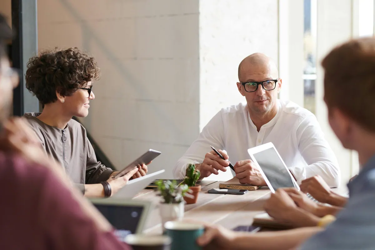 Colleagues meeting around a table with laptops and tablets